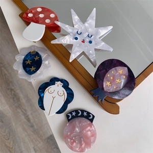 Artistic acetate hair clips with mushroom and star patterns in a mirror reflection