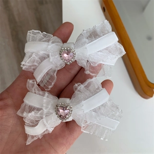 Detail view of handmade white lace bow hair clips with a sparkling pink heart-shaped crystal