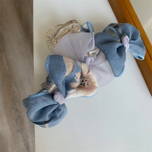 Détail d'une pince à cheveux avec nœuds en tissu bleu et blanc et motifs floraux