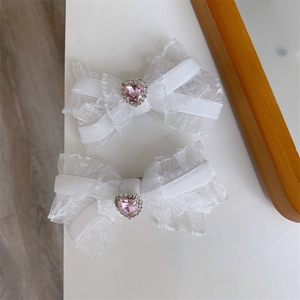 Detailed view of white lace bow hair clips featuring a pink heart crystal center