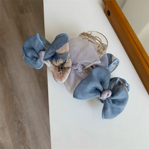 Détail d'une pince à cheveux avec nœuds en résille bleu et violet à motif floral