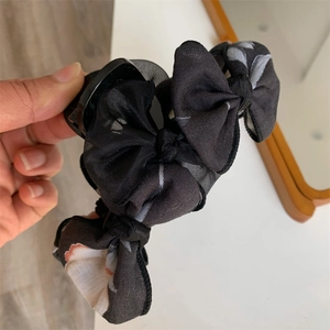 Détail d'une pince à cheveux avec nœud en maille noire et imprimé floral bicolore