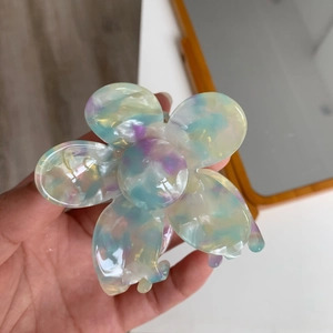 Detailed view of flower-shaped hair claw clip in pastel multi-color acetate finish
