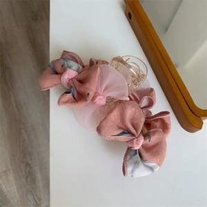 Gros plan d'une pince à cheveux à nœud en mousseline rose sur surface blanche