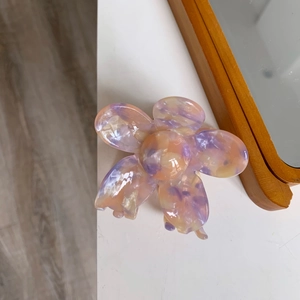 Detail view of the purple and orange marble texture on a five-petal floral acetate hair claw