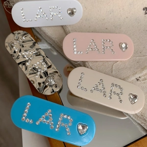 Détail de pinces à cheveux en strass en forme de cœur avec lettres LAR et marbre