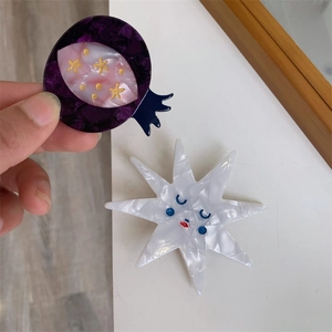 Detailed macro view of handmade acetate pomegranate and star hair clips with artistic textures