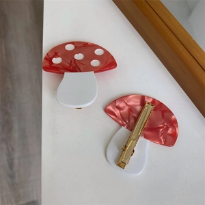 Detailed view of handmade acetate mushroom hair clips with red marble pattern