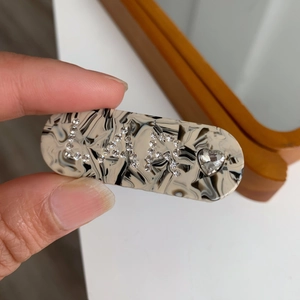 Détail d'une pince à cheveux en acétate marbré avec lettres LA en strass et cristal cœur