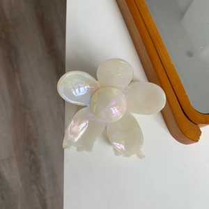 Detail view of the iridescent pearlescent finish on the white five-petal flower hair claw