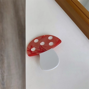 Close-up of handmade acetate mushroom hair clip with red marble texture and white dots