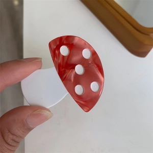 Macro shot of a red and white mushroom hair clip with unique marble texture patterns