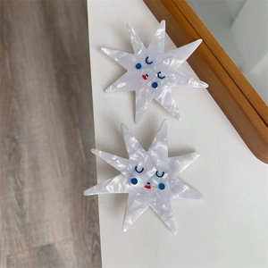 Detail of two handmade acetate star hair clips with cute marble texture and playful faces