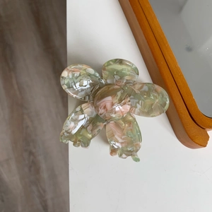 Detail of marble pattern acetate flower hair claw clip with glossy green and pink finish