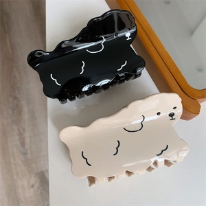 Detail view of cartoon dog hair claws in black and beige acetate with glossy finish