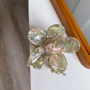Detail view of the floral hair claw clip featuring pink and green marble acetate textures