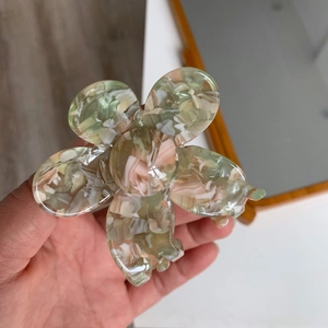 Detail of flower hair claw clip with green, white, and orange marbled acetate texture