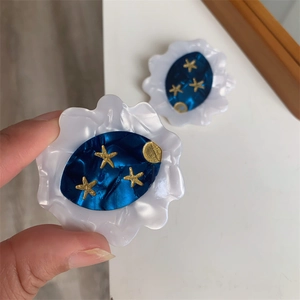 Detail showing a celestial acetate hair clip with moon and star pattern in blue and gold