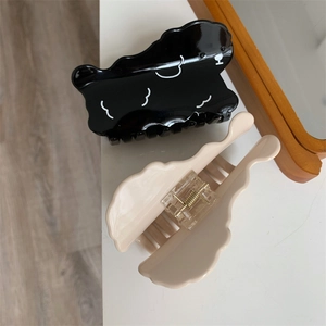 Detail of wavy acetate hair claws featuring a cute puppy pattern and metal spring mechanism