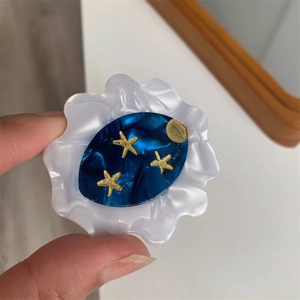 Detail of celestial hair clip with golden stars and moon on blue acetate wave base