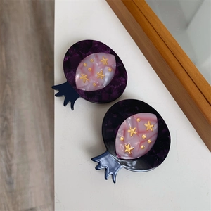Detailed close-up of pomegranate-shaped acetate hair clip with golden star accents