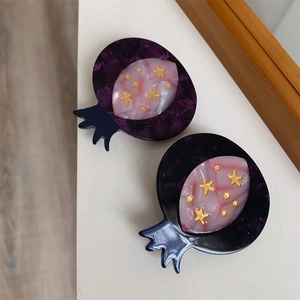 Detail of acetate pomegranate hair clips with marble texture and golden star patterns