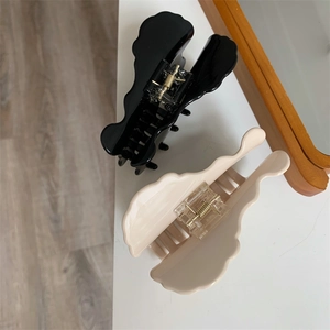 Detail of glossy black and cream wavy hair claw clips with strong gold metal springs