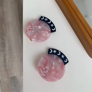 Detailed macro view of pink marble acetate hair clips with moon and star patterns