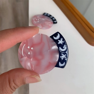 Close-up of handmade pink marble acetate hair clips with moon and star details
