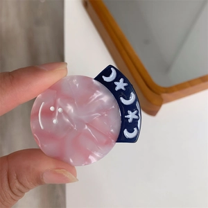 Detail showing pink marble texture phone grip with smiling face and blue crescent moon
