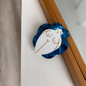 Close-up of handmade flower hair clip with deep blue wavy edge and abstract female torso art