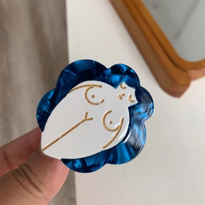 Detailed view of wave-edged acetate hair clip featuring gold artistic female form design