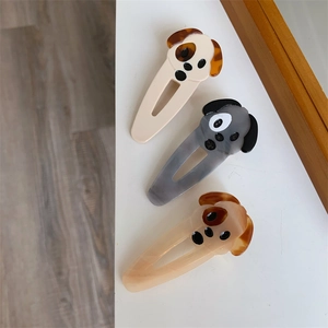Detailed view of three puppy-shaped hair clips in acetate with natural marble patterns