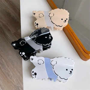 Detalle de tres pinzas para el pelo con forma de perro en acetato beige, negro y blanco