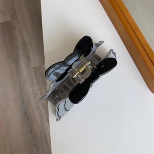 Dettaglio di una creativa pinza per capelli a farfalla con meccanismo a molla dorato