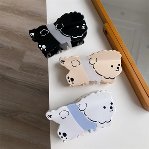 Vista detallada de tres pinzas para el pelo de acetato con forma de perro teddy en negro y beige