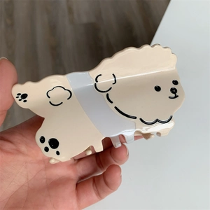 Primer plano de una bonita pinza para el pelo de acetato crema con forma de perro