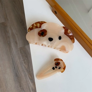 Detail view of two acetate puppy hair clips with marble texture on a white surface