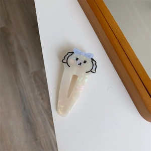 Dettaglio del fermaglio per capelli in acetato con texture perlata e design a cane