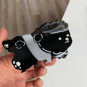 Primer plano de una pinza para el pelo con forma de perro en acrílico blanco y negro