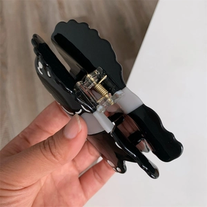 Detalle de una pinza para el pelo de gato en material de acetato blanco y negro premium