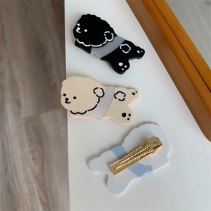 Detailed view of Bichon dog hair clips in beige and black with golden metal clips