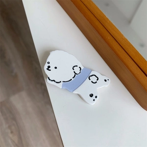 Detail shot of cute white cartoon dog hair clip on a natural wood and white background