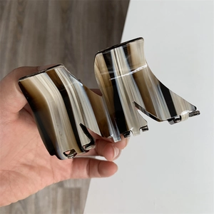 Detail view of M-shaped acetate hair claw clip with marble texture held in hand