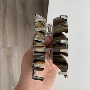 Close-up of a large marble patterned acetate hair claw clip with metal spring detail