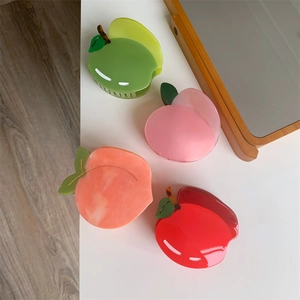 Dettaglio di pinze per capelli a forma di frutta con design a mela e pesca e molla in metallo