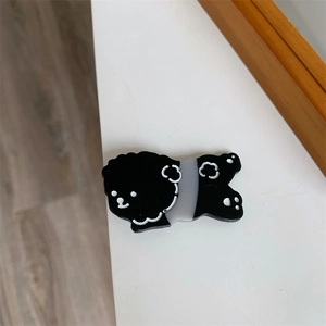 Close-up of a cute black and white cartoon dog hair clip made of resin on a white surface