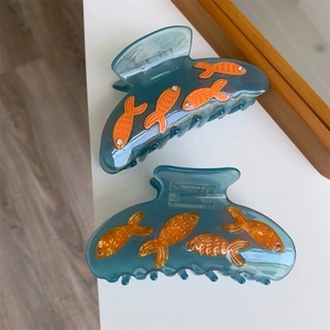 Gros plan de pinces à cheveux bleues avec motifs poissons orange et strass étincelants