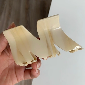 Macro shot of large cream M-shaped acetate hair claw clip with marble texture detail