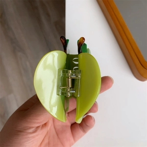 Dettaglio ravvicinato di una molletta per capelli a forma di mela verde con motivo tartarugato